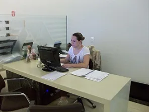 Posto de atendimento do showroom, com computador e orçamentos sobre a mesa