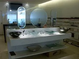 Showroom com bancadas, cubas e espelhos redondos em exposição