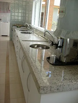 Cozinha com bancada longa de granito claro e duas cubas