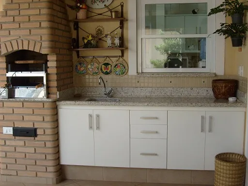 Área gourmet com churrasqueira de tijolo e bancada de granito bege