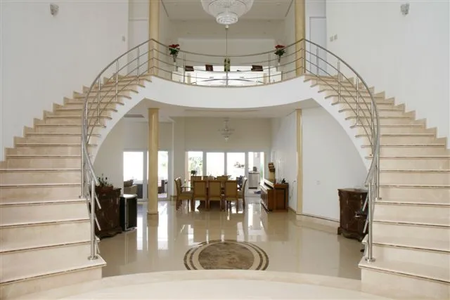 Hall de entrada com escada curva e piso claro com medalhão central