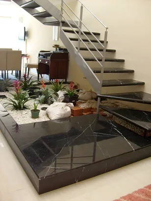 Escada e base revestidas em mármore preto com veios brancos, em sala de estar