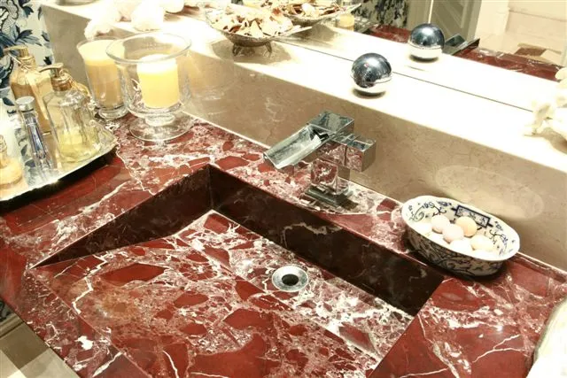Bancada de mármore vermelho com veios brancos e cuba esculpida na pedra
